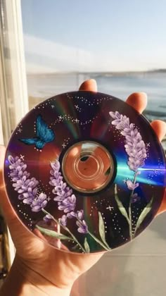 a person holding up a cd with purple flowers on the front and blue butterflies on the back