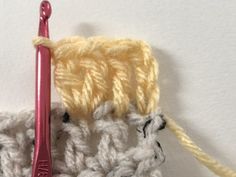 a crocheted object is shown with a knitting needle in the foreground and on the right side