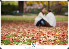 two people sitting on the ground surrounded by leaves