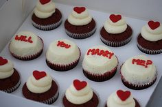 twelve cupcakes with white frosting and red hearts on them in a box