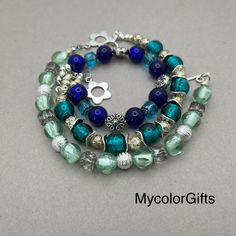 three bracelets with blue and green glass beads on each bead, one has a silver charm