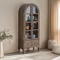 a tall wooden cabinet sitting in the corner of a living room next to a window