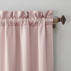 pink curtains hanging on the side of a wall with a curtain rod in front of it