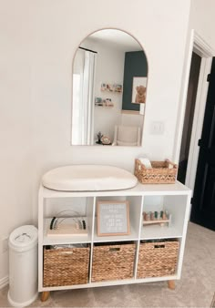 there is a white shelf with baskets on it and a mirror in the corner behind it