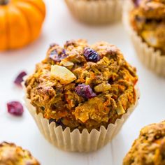 several muffins sitting on top of a white table next to small pumpkins