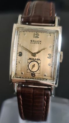 Men's 1940s Rolled Gold GRUEN VERI-THIN 15 Jewels Mechanical Deco Style Tank Watch Condition  (See photos for full details) Case, Excellent vintage condition, Rolled Gold. 25.6 x 25.6 mm excluding the crown and lugs Bracelet/strap, Tan leather with pin buckle    Dial, Champagne coloured excellent  vintage condition with gold tone Arabic Numeral markers.  Hands, Gold tone with subsidiary seconds.  Wrist size, upto 19.5 cm  Crystal,Mineral glass, Excellent vintage condition.  Fully working and kee Tank Watch, Retro Watches, Champagne Color, Wristwatch Men, Crystals Minerals, Wrist Watches, Deco Style, Tan Leather, Favorite Jewelry