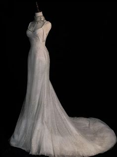 a white wedding dress on display in front of a black background with the back of it's neckline