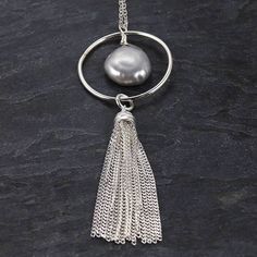 Our sterling silver and freshwater pearl tassel necklace is a trendy yet delicate piece of jewelry. This would make a great gift for the girl that loves subtle statement necklaces that are easy to wear. Details The necklace is 32.5 inches long The tassel and circle component are a little 2.5 inches long. Since the necklace is so long, there is no clasp making it easy to take on and off. The freshwater pearl is an iridescent gray with hints of purple and green hues. Please note that each pearl ma Elegant Dangle Tassel Necklace, Bohemian Silver Tassel Necklace Gift, Silver Bohemian Tassel Necklace As Gift, Elegant Tassel Necklace For Party, Elegant Long Tassel Necklace, Bohemian Lariat Necklace With Tassels For Gifts, Party Necklaces With Tassels And Dangle Shape, Bohemian Lariat Necklace With Tassels As Gift, Tassel Necklace As Gift