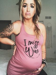 a woman with tattoos on her stomach posing for a photo in front of a bed