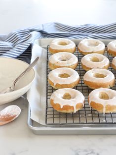 glazed donuts sitting on top of a cooling rack next to a bowl and spoon