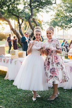 two women standing next to each other in front of a table with cake on it