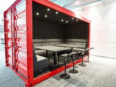 a large red container sitting inside of a dining room filled with tables and stools