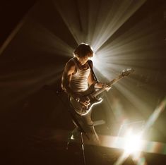 a man with a guitar on stage in the dark