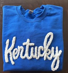 Show your school spirit in this cute sweatshirt. Comfort, casual and loose fitting, made on 50/50 cotton/poly blend shirts.  Embroidered chenille yarn, Kentucky sweatshirt.  We can do other states and different color combinations. Just leave a note at checkout.  You can follow us at the below link for chances to win giveaways and to see all of our latest creations.  https://www.facebook.com/groups/710060383256657/?ref=share&mibextid=S66gvF Casual Winter Sweatshirt For Cheerleading, Casual Sweatshirt For Cheerleading In Winter, Cotton Sweater With Ribbed Cuffs For Game Day, Pre-shrunk Crew Sweatshirt For School Spirit, Cotton Sweatshirt With Ribbed Cuffs For Fan Gear, Blue School Spirit Sweatshirt For Fans, Cotton Hoodie With School Spirit Style, Blue Sweatshirt For School Spirit, Cotton Hoodie For School Spirit