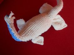 a knitted gecko laying on top of a red surface