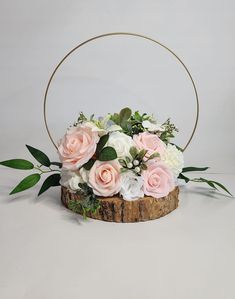 a flower arrangement in a wooden basket with greenery and white flowers on the side