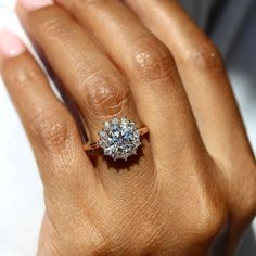 a woman's hand with a diamond ring on top of her finger and the other hand holding an engagement ring