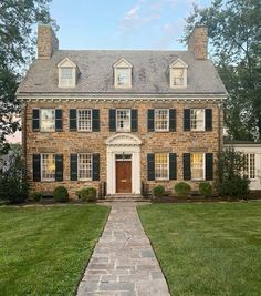 an old brick house with black shutters on the front and side windows, along with a stone walkway leading up to it