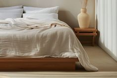 a bed with white linens and pillows in a neutral colored bedroom, next to a window