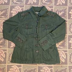 Features Pockets On The Waist, Button Up Pockets On The Chest, And Button Up Cuffs. Has Camo Lining On The Inside Of Jacket. In Great Condition. Never Worn, No Tears, But Has Small White Spots From Steamer On The Back And On The Back Of One Sleeve As Pictured. Tag Says Size Medium, But Fits Like Size Small. Measurements: 27” Inches In Length, 38” Chest, 42” Waist When Buttoned, And 22” Sleeves. Double-breasted Cotton Blazer With Buttons, Casual Green Double-breasted Outerwear, Green Utility Jacket With Buttoned Pockets, Fall Utility Blazer With Buttons, Green Long Sleeve Utility Jacket With Buttoned Pockets, Winter Utility Blazer With Button Closure, Utility Blazer With Button Closure, Casual Double-breasted Outerwear With Buttoned Pockets, Classic Green Utility Jacket With Buttons