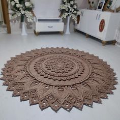 a large round rug on the floor in a room with white furniture and flowers behind it