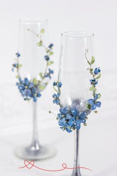 two wine glasses decorated with blue flowers and greenery