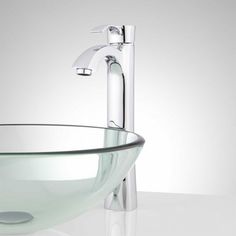 a glass bowl sink with chrome faucet and metal spouted faucet