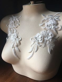 a mannequin with white flowers on it's chest and two small beads attached to the back