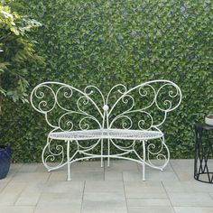 a blue bench sitting in front of a green wall covered with leaves and vines next to a potted plant