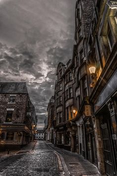 an empty city street with buildings on both sides and dark clouds above it in the sky