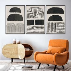 an orange chair sitting in front of two black and white art pieces on the wall