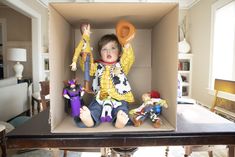 a little boy sitting in a box with toys