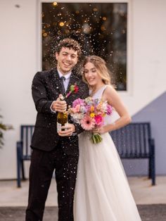 a newly married couple standing in front of a building with confetti falling on them