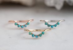 three rings with turquoise stones on them sitting on a white counter top next to a rock