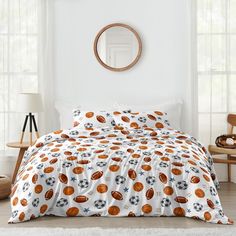 a bed with a comforter and pillows on top of it in a white room