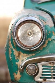 the front end of an old green car with rust on it's grills