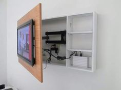 a tv mounted to the side of a white wall next to a wooden framed object