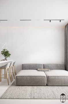 a living room with a couch, table and chairs in front of a white wall