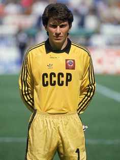 a soccer player standing on the field with his hands in his pockets and looking at the camera