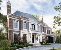 a large brick house with lots of windows and plants around it's front entrance