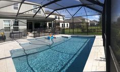 an outdoor swimming pool surrounded by patio furniture and glass doors that open up to the backyard