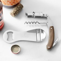 a bottle opener, corkscrews, and beer bottles on a white surface