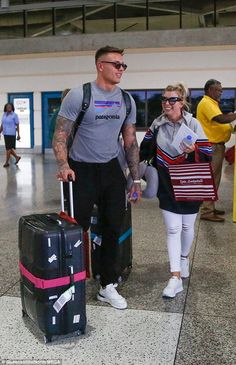 a man and woman walking through an airport with luggage