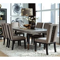 a dining room table and chairs in front of a large window with an area rug on the floor