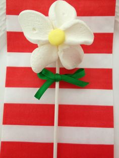 a white flower sitting on top of a red and white striped napkin