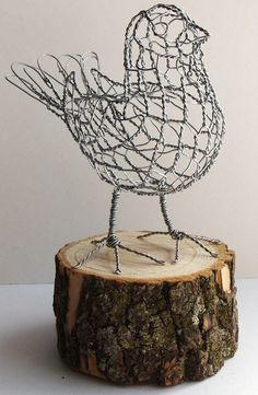 a wire bird sculpture sitting on top of a tree stump