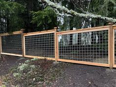 a wooden fence with glass panels on top and trees in the back ground behind it