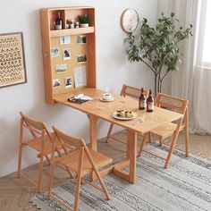 a wooden table and chairs in front of a wall mounted cabinet with pictures on it