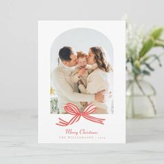 a christmas card with an image of a man and woman holding a baby in their arms