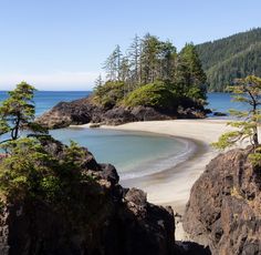 the beach is surrounded by rocks and trees